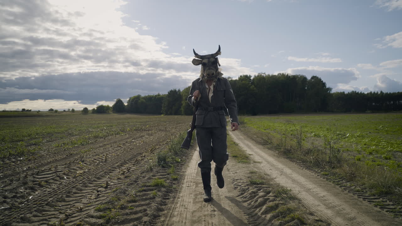 A Soldier with a Cow Mask Walking Through a Field