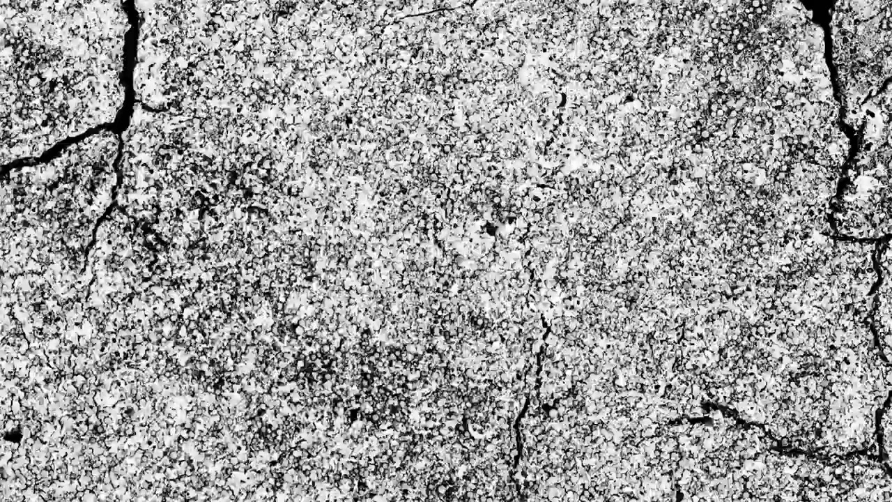 Primo piano ad alto contrasto di una texture di asfalto danneggiato