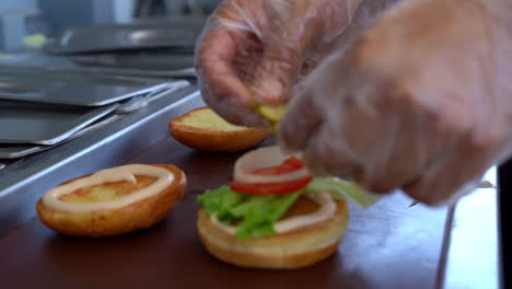 chef-is-preparing-burger-sandwiches-and-putting-vegetables-on-bread