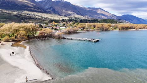 aerial footage captures glenorchy's serene landscape with mountains, lake, and vibrant autumn foliage under clear skies