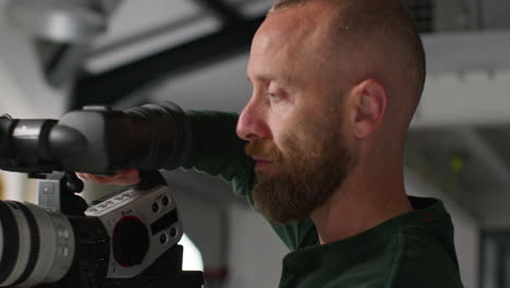 primer plano de un operador de cámara de cine masculino quitando la cámara del trípode grabando una película o video en el estudio