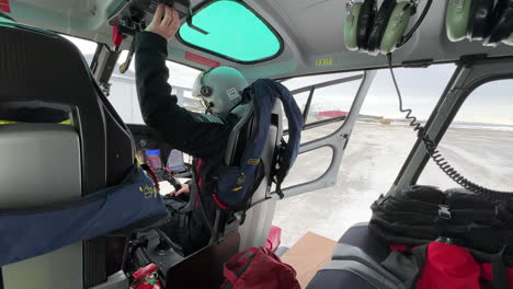 pilot starting the engine of a helicopter during cold winter conditions