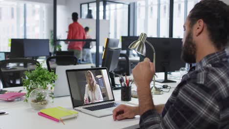 Middle-eastern-man-talking-on-video-call-with-female-office-colleague-on-laptop-at-office