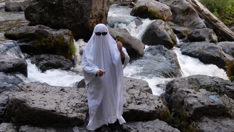 the river flows behind a dancer doing a social media trend dressed as a ghost