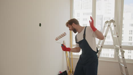 man painting a wall in a room under renovation