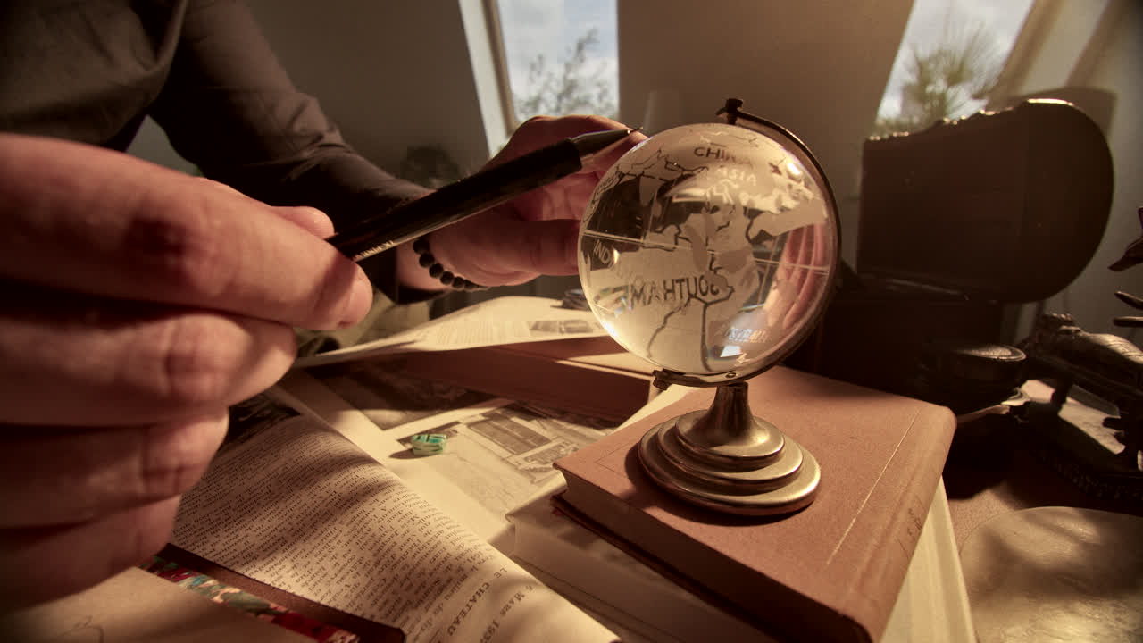 Person Examining a Crystal Globe on a Vintage Desk