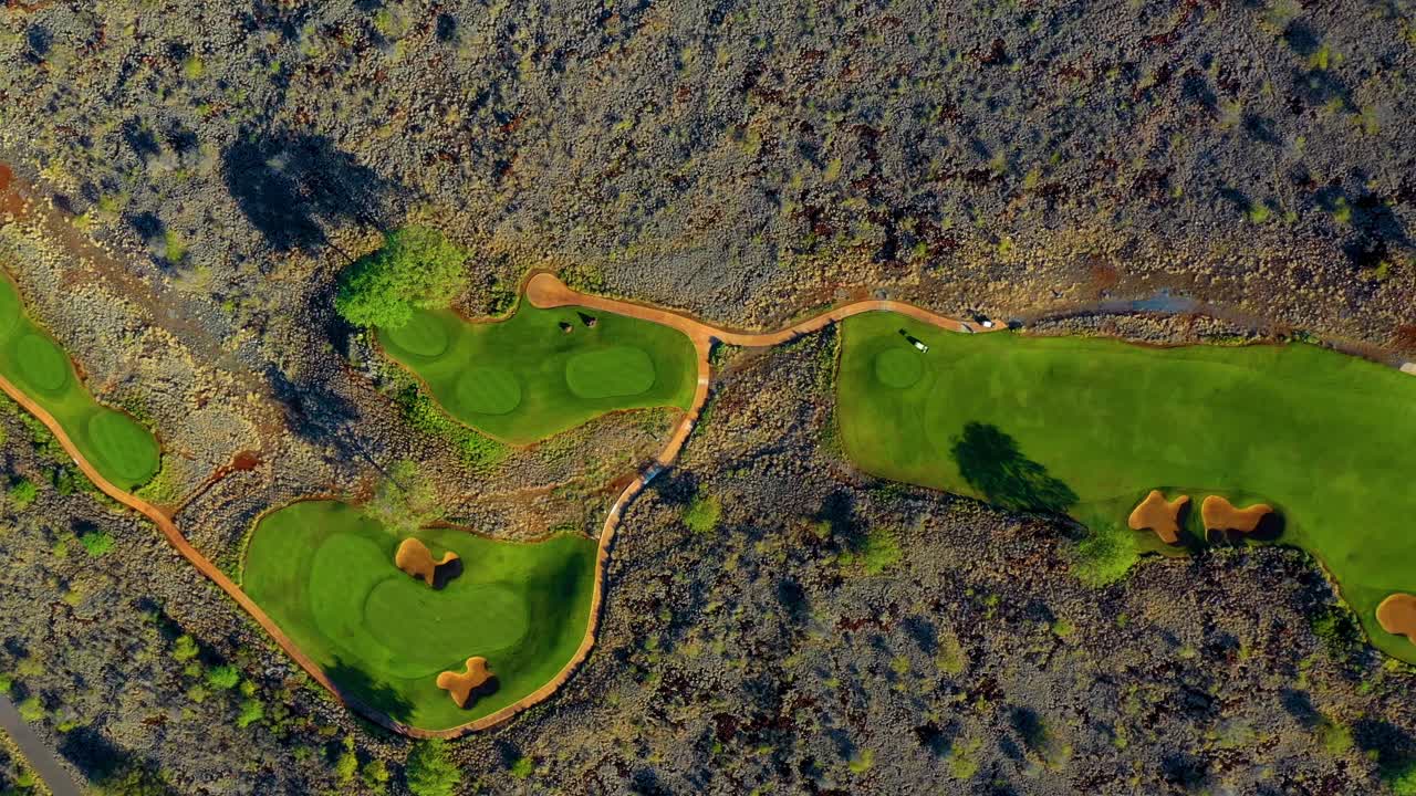 vista aérea de arriba hacia abajo del campo de golf manele bien cuidado que se destaca contra el paisaje accidentado - lanai, hawaii