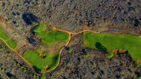 aerial top down view of well-kept manele golf course standing out against rugged landscape - lanai, hawaii