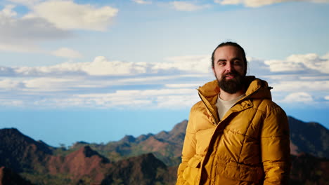 thrilled traveler raises his arms in triumph after climbing the mountain top