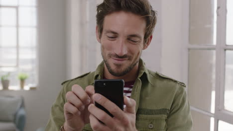 Retrato-En-Cámara-Lenta-De-Un-Joven-Apuesto-Sonriendo-Disfrutando-De-La-Navegación-De-Mensajes-De-Texto-Usando-Un-Teléfono-Inteligente