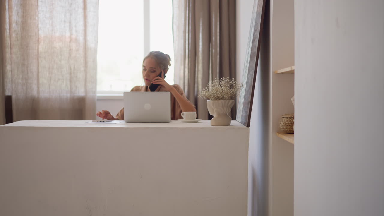 Blonde woman works on computer talking on phone in office