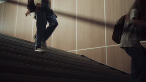 group teenagers running downstairs school corridor. children stepping stairway.