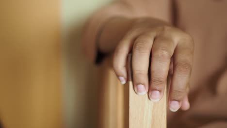 close up of a hand resting on a wooden chair