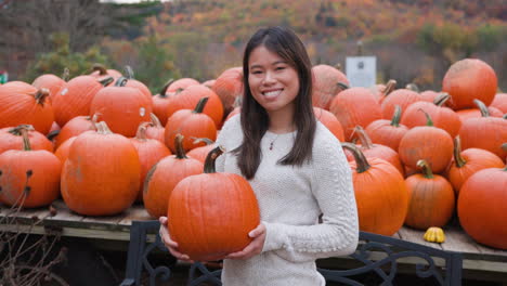 attractive young asian woman holding a pumpkin and smiling