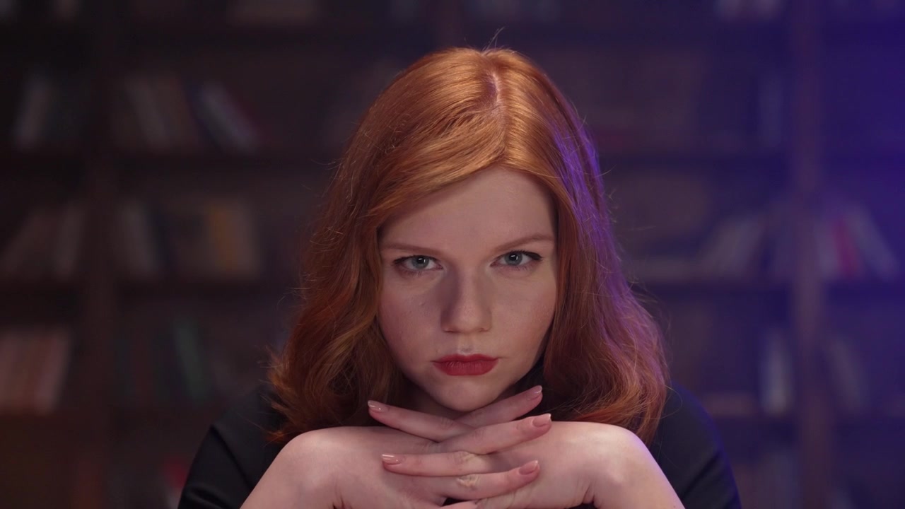 Serious Redhead Woman Looking at Camera with Clasped Hands