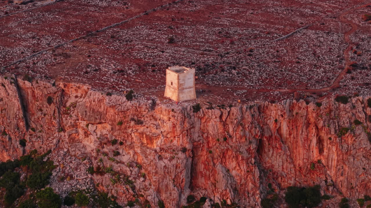 Historic tower on Sicilian cliff at sunset with reddish hues