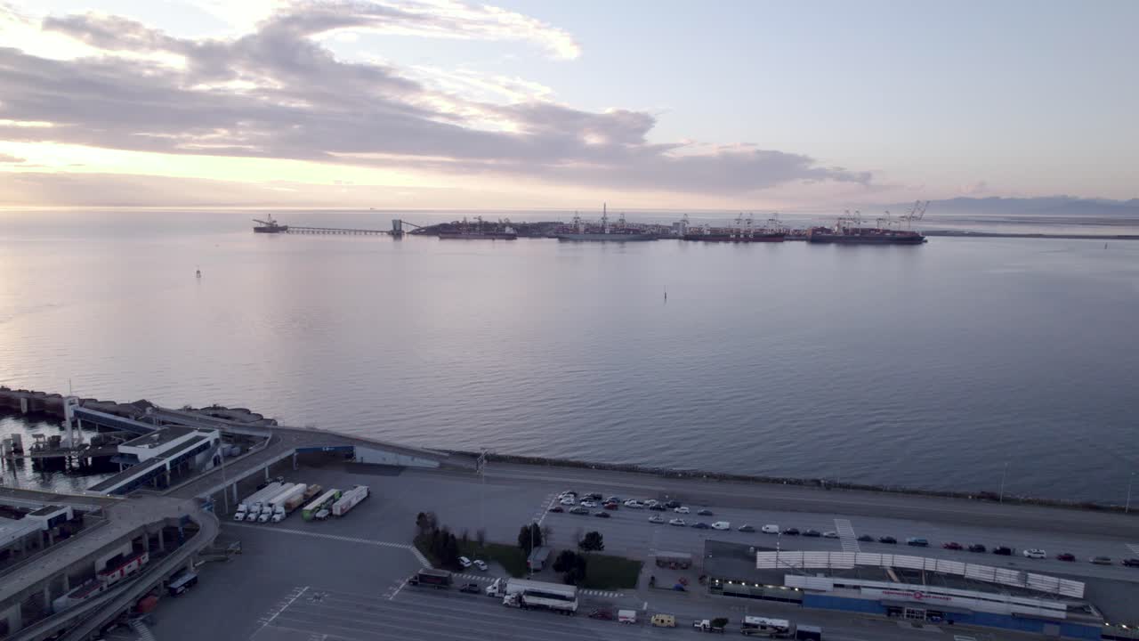 puesta de sol aérea paisaje marino de vancouver canadá tsawwassen bc terminal de ferries, silueta a la distancia de la grúa portuaria para cargar el barco de carga