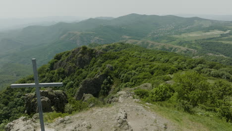 Dreamy-scenery-of-a-Christian-cross-on-top-of-wild,-forested-hills-nearby-Kojori