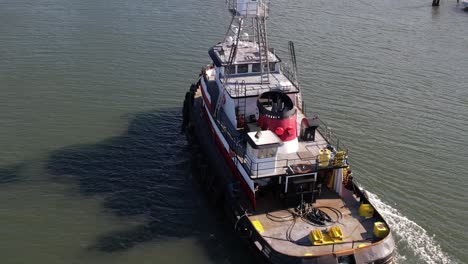 an aerial view behind a tugboat on a sunny day in the east rockaway inlet in queens, ny