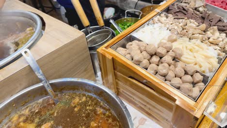 street food stall with boiling noodle soup and meatballs