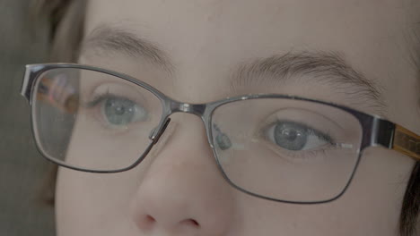 primer plano de un chico lindo con ojos azules y gafas viendo la televisión