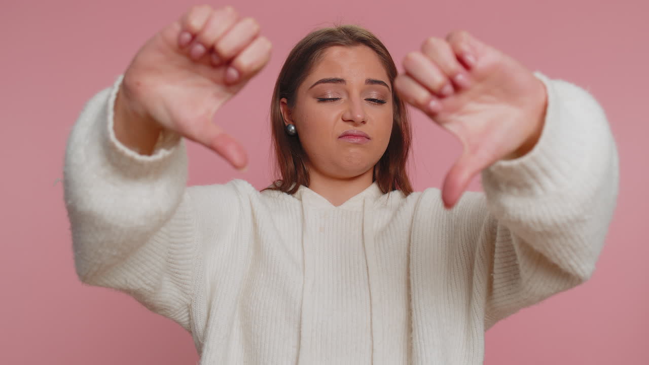 ⁇  스웨터를 입은 화가 난 여성이 엄지손가락을 아래로 내리고 표시 제스처, 불쾌감, 불만을 나타 ⁇ 니다.