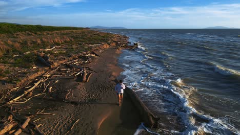 Una-Mujer-Joven-Corriendo-Trotando-En-Una-Playa-De-Arena-Al-Atardecer-Haciendo-Entrenamiento-Deportivo-Activo-Para-Maratón-Y-Manteniéndose-En-Forma,-Un-Cuerpo-Sano,-Músculos-Y-Resistencia