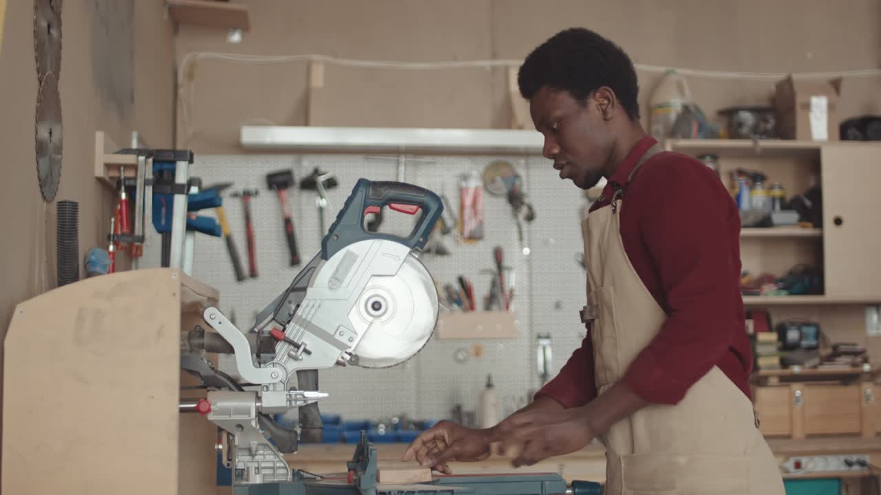 carpintero afroamericano que usa una sierra circular mientras trabaja