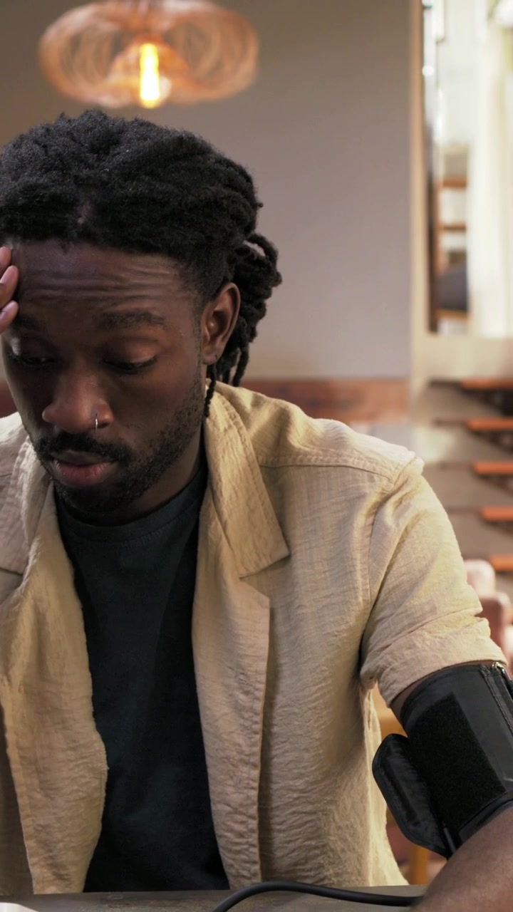 Vertical video: Cuff inflating, man reading monitor and touching device at table, monitoring health