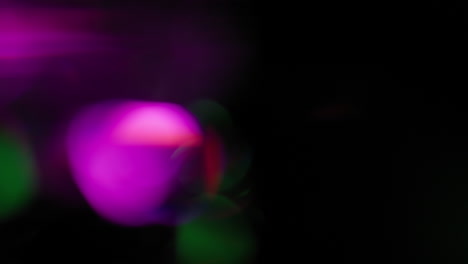 green and purple light leaks glowing on black background
