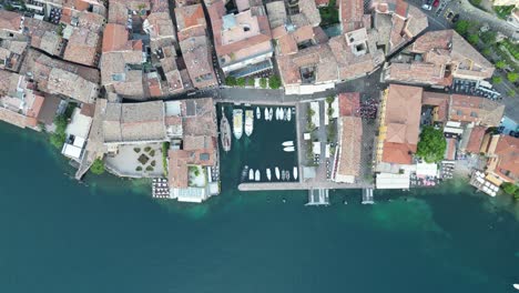 Vista-Asombrosa-De-Pequeños-Botes-Alineados-En-El-Pequeño-Puerto-En-El-Lago-De-Garda-En-Malcesine,-Italia