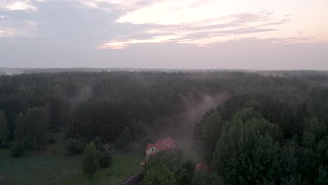 Drone-flight-over-a-foggy-forest-during-sunset