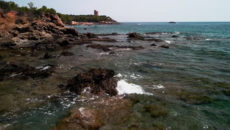 waves crash onto outcrops at shoreline on summer in sardinia, italy