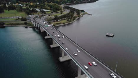 Luftaufnahme-Von-Fahrzeugen,-Die-Auf-Einer-Brücke-über-Einen-Ruhigen-Fluss-Fahren