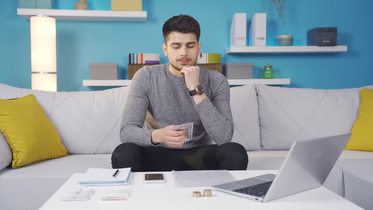청년이 청구서를 지불하고, 계산기를 사용하고, 예산을 확인하고 있습니다.