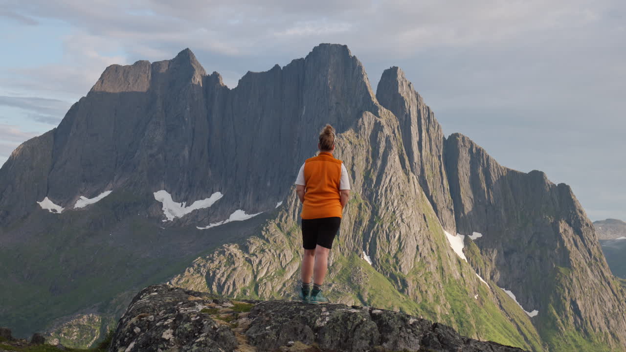 Back of female hiker in front of jagged arctic mountain in Senja Norway