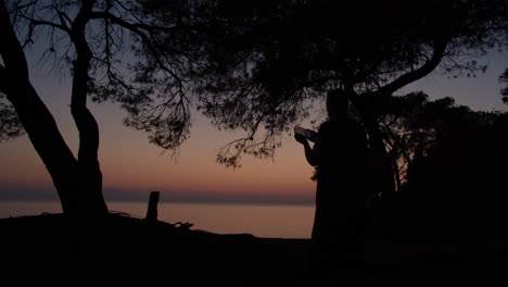 silhouetted girl capturing serene sunset