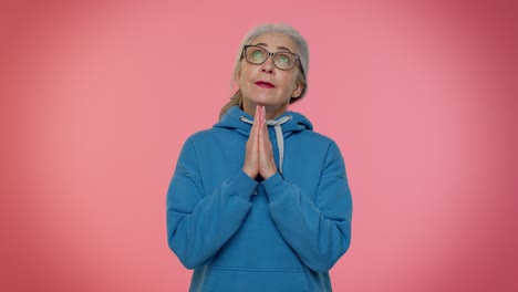una anciana madura orando a dios haciendo un deseo pidiendo con expresión de esperanza implorando disculpas