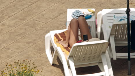 beautiful young women relaxing on the deck chair near the pool