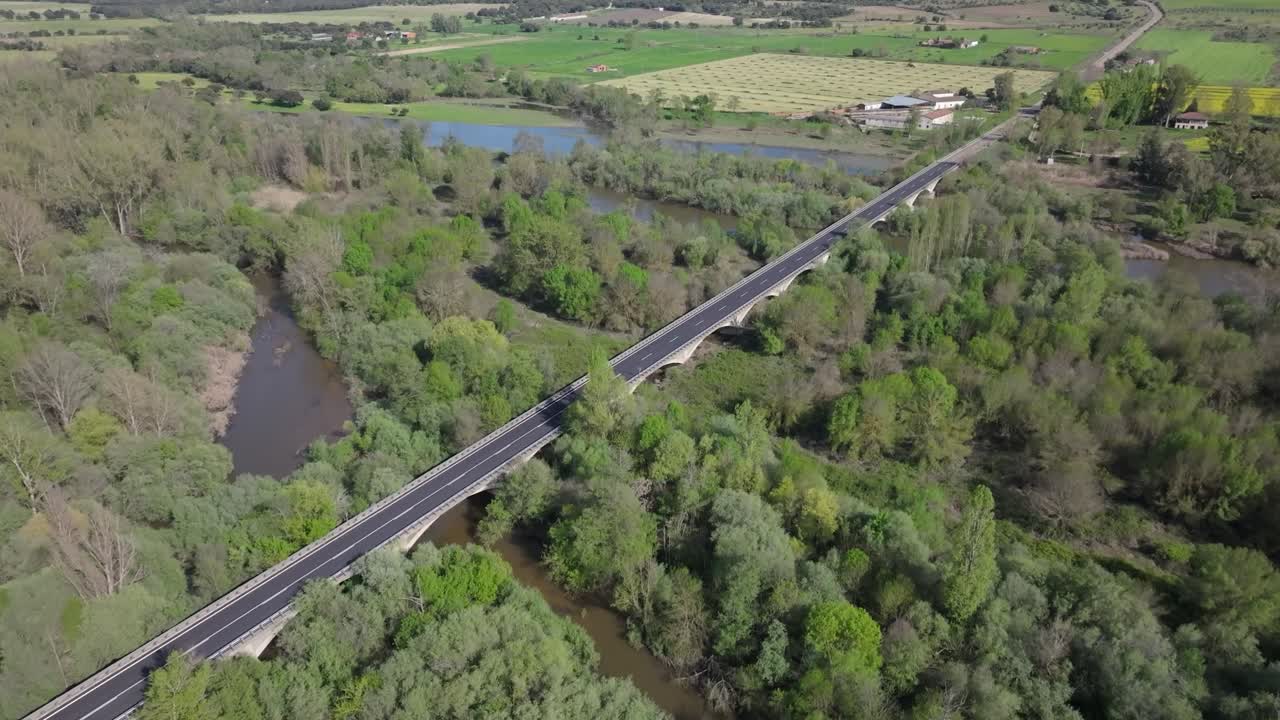 Beautiful drone flight over a wide muddy river and a large bridge in a green landscape. The river splits into two branches at the bridge, and the riverbank details are clearly visible in slow motion.