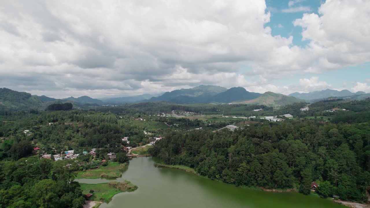 Drone zoom in shot over green mountains and lake in Cobán, Guatemala on a sunny day