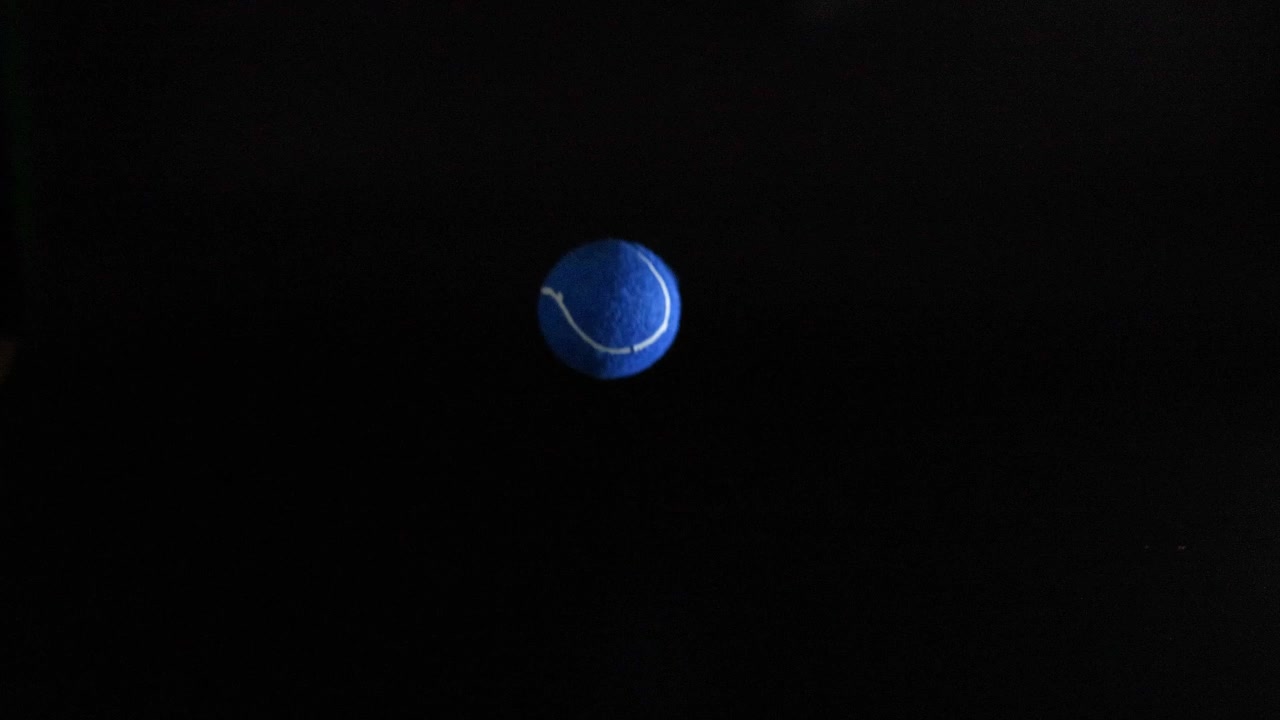 A tennis ball bouncing in dark background