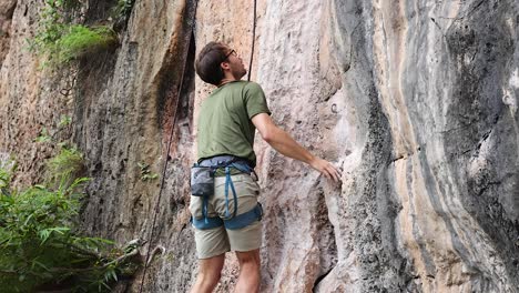 climber ascends limestone cliff in krabi, thailand