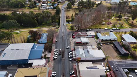 aerial drone footage smoothly tracks over a road bridge crossing a riverbank in a small residential area, under bright natural daylight