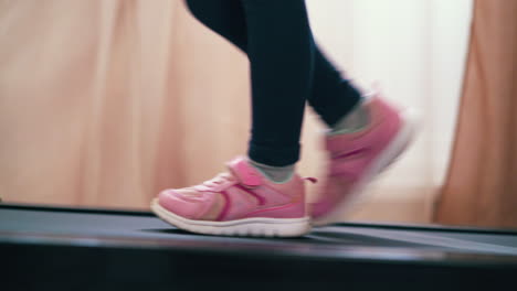 girl-in-black-leggings-walks-along-modern-treadmill-at-home