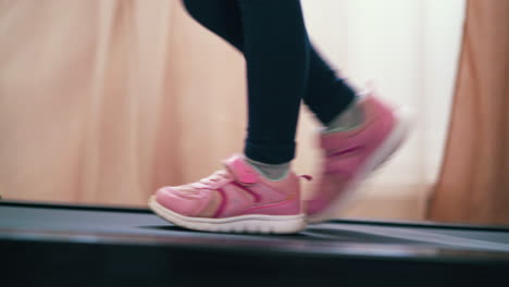 girl in black leggings walks along modern treadmill at home