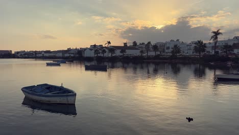 puesta de sol sobre un lago tranquilo con barcos y la ciudad