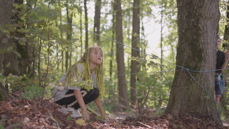 children in a summer camp hike crawls on the ground. training of passing obstacles by crawling on the ground. a girl tumbles in the forest on a camp assignment