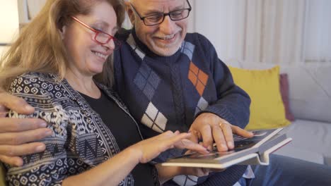 pareja feliz teniendo emociones positivas y hablando mientras miran el álbum de fotos.