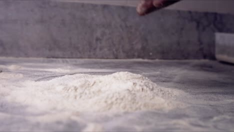 pizza dough being throw to a table with flour